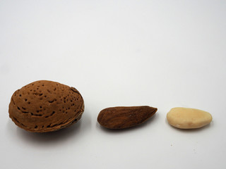 Tres almendras, Una con su cáscara, otra con piel y otra pelada.