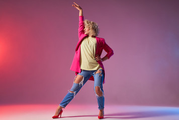 Young dancer showing modern dance movie, training in dancing studio, exercising r and b element, standing on heels with raised hand, looking away, ready to start moving