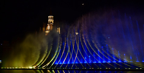 Colorful water fountains. Beautiful laser and fountains show. Large multi colored decorative dancing water jet led light fountain show at night. Dark background.