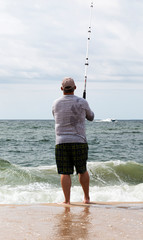 Rear view of man surfcasting on the beach