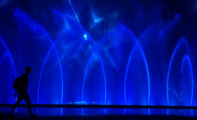 Colorful water fountains. Beautiful laser and fountains show. Large multi colored decorative dancing water jet led light fountain show at night. Dark background.