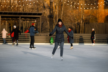 girl ice skating at a public ice rink. girl is skating at a public ice rink. beautiful autumn view of the city ice arena
