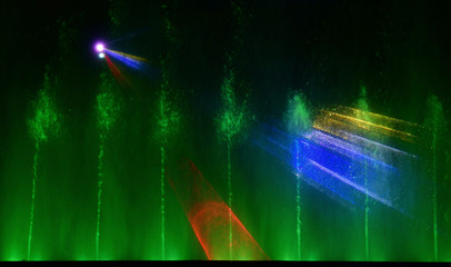 Colorful water fountains. Beautiful laser and fountains show. Large multi colored decorative dancing water jet led light fountain show at night. Dark background.