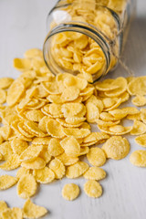 Corn flakes in a glass jar on white wooden surface. Top view. Place for your text