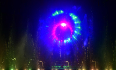 Colorful water fountains. Beautiful laser and fountains show. Large multi colored decorative dancing water jet led light fountain show at night. Dark background.