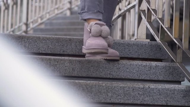 Woman walks down the stairs in purple ugg winter boots