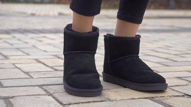 Female cheerful legs in black ugg winter boots close up 