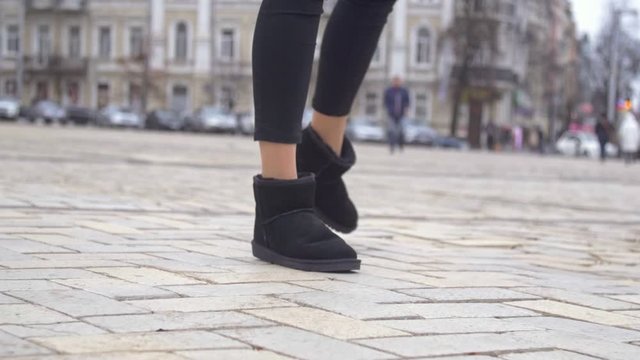 Close up of female cheerful dancing in black ugg winter shoes