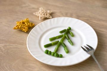 Edible Christmas tree made of green beans and peas on wooden background. Vegetarian meal for holidays. Food for kids