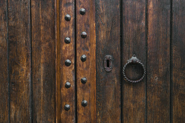 Wooden rustic antique aged dark brown gate door with metal knocker. Decorative furniture, backdrop for desktop, architecture design, carpenter. Copy space