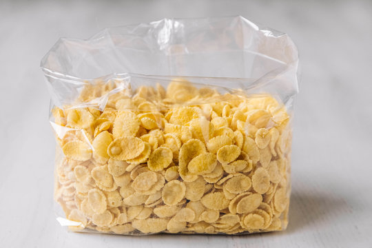 Cornflakes in plastic bag on white wooden surface. Place for your text