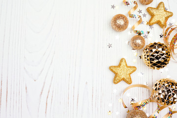 New Years Eve side border of confetti, streamers and gold decorations. Overhead view on a white wood background.