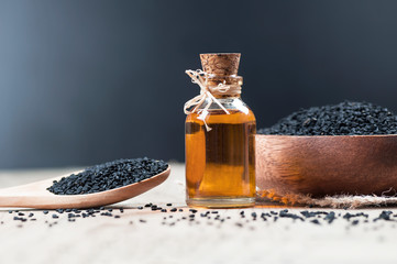 glass bottle of black cumin seeds essential oil , Nigella Sativa in spoon on wooden background....