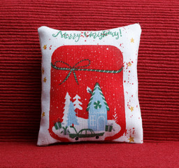 Red pillow with christmas scene on the sofa