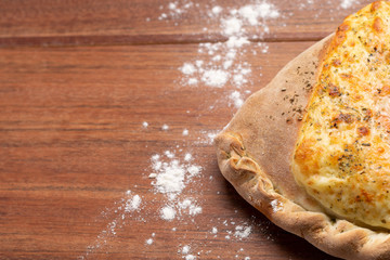 Closed calzone pizza on wooden background