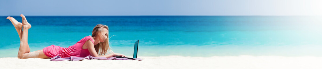 Blond girl with a laptop on tropical beach