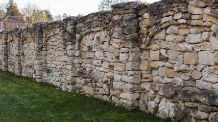 Masonry, limestone sandstone fence. A beautiful stone fence lined with uneven pieces of limestone bricks