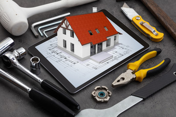 Tablet with construction tools and 3d home plan concept