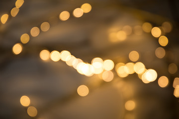 Christmas garlands with blurred focus in the form of bokeh and Golden misty haze on a dark background. Abstract colorful background with Golden bokeh.