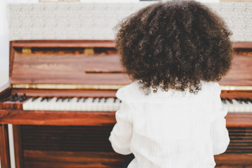 Beautiful little African American girl smile happy playing and learning piano classroom in holiday...