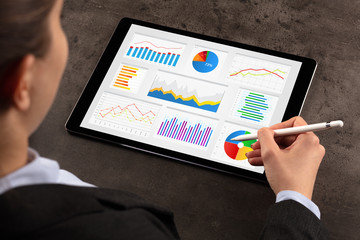 Elegant business woman making diagrams on tablet with pencil