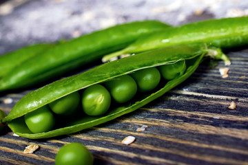 open string of green peas on a wooden table closeup