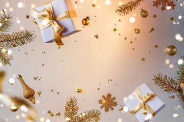 Merry Christmas and New Year background. Xmas holiday card made of flying decorations, gold fir branches, balls, snowflakes, sparkles, gift boxes, bokeh, light on golden background. Selective focus