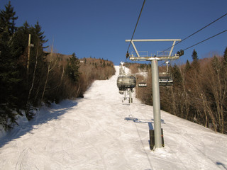 skiers and snowboarders are sitting on a ski cable chair lift