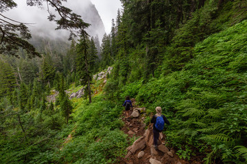 Adventurous Girl is hiking in beautiful green woods in the mountains during a cloudy summer morning. Taken on Crown Mountain, North Vancouver, BC, Canada.