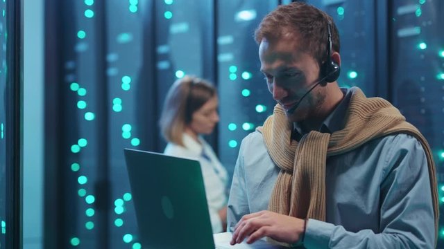 Professional IT specialist working on laptop diagnosing supercomputer typing on keyboard causing blackout server error. Power failure in data center. Fun scene.