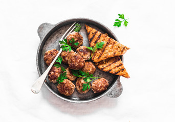 Fried meatballs in a frying pan on a light background, top view