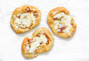 Puff pastry, ham, mozzarella cheese breakfast pizza on a light background, top view