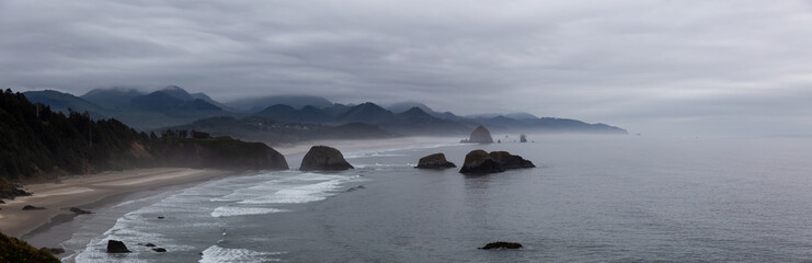 Cannon Beach, Oregon, United States. Beautiful Aerial Panoramic View of the Rocky Pacific Ocean Coast during a cloudy summer sunrise.