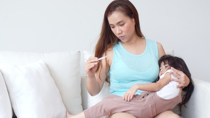 Young mother examined her daughter with a thermometer