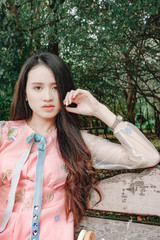 Naklejka premium Portrait of beautiful young asian woman sitting in garden on bench