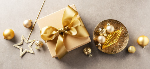 Gift box with golden ribbon on grey background