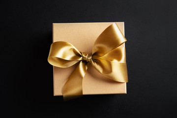 Gift box with golden ribbon on dark background