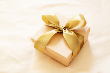 Gift with golden ribbon on golden background