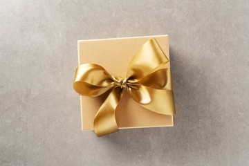 Gift box with golden ribbon on grey background