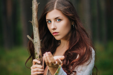 Young beautiful girl in medieval cowboy clothes, with a stick in hand. Barefoot on the ground....