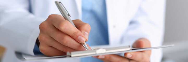 Female doctor arm hold silver pen and pad during