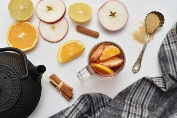 Hot aromatic Christmas tea with apples, orange, lemon, cinnamon and brown sugar, flat lay with iron tea pot and warm plaid.