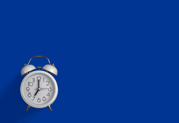 a white alarm clock with a dark blue background.
