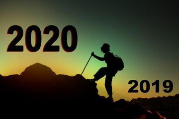silhouette of people climbing on the mountain with sign show that people going new year form 2019 to 2020
