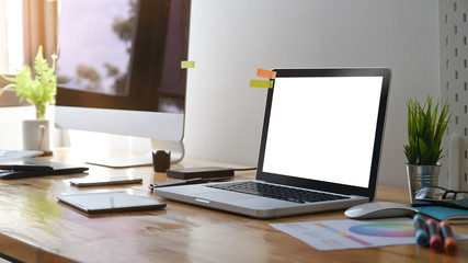 Side view mockup laptop computer on creative graphic design workspace with blank screen.