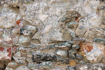 Texture of an old heavily damaged stone wall coated with cement residues