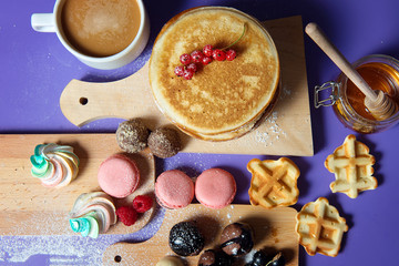 Fototapeta na wymiar Pancakes with honey and sweets on a purple background, top view.