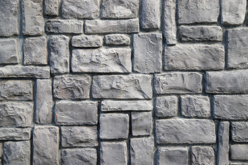 Texture of a stone wall made of rectangular blocks of different sizes painted in gray