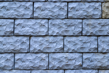 Texture of a wall made of rough stone blocks painted in blue