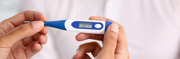 hands of a female doctor holding a thermometer